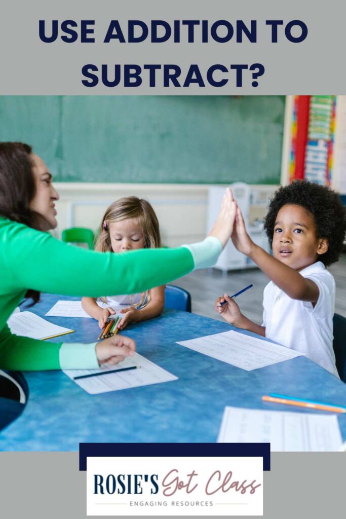 teacher at a table with a small group of children working on subtraction and teacher is giving a student a high five